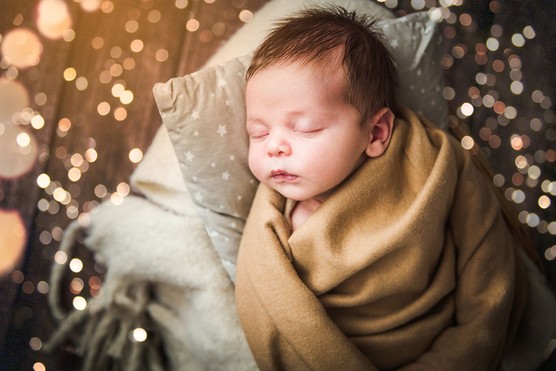 baby boy lying asleep surrounded by magical lights