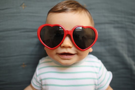 Baby boy wearing red heart sunglasses