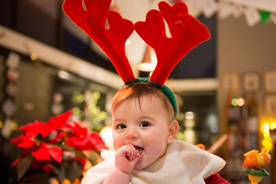baby led weaning at christmas: baby wearing reindeer antlers and feeding herself