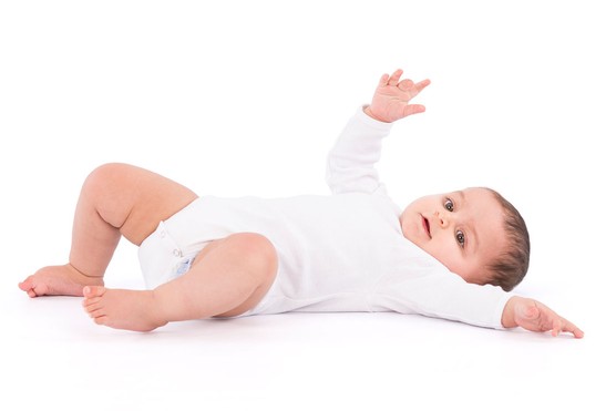 baby in white babygro rolling over from front to back