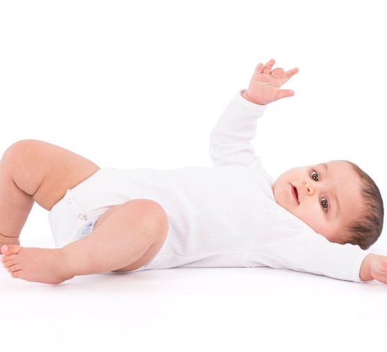 baby in white babygro rolling over from front to back