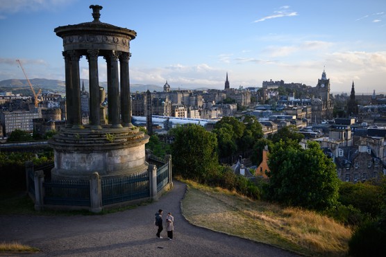 Pedestrians stand next to the Nelson Monument with a general view of Edinburgh in the background, on the east coast of Scotland, on August 20, 2024.