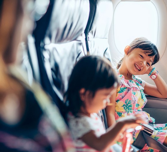 little girls sitting next to their mothers on an airplane