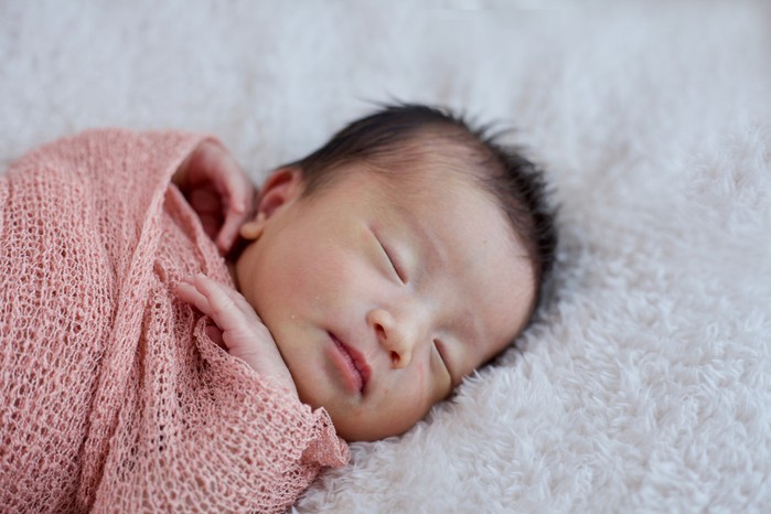 newborn baby girl lying on fluffy blanket
