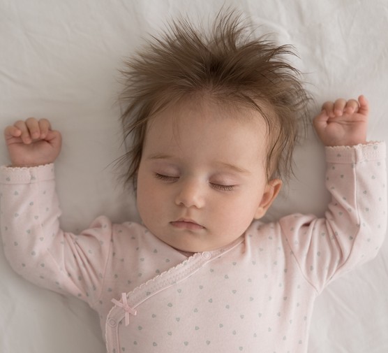 baby sleeping on her back in a cot
