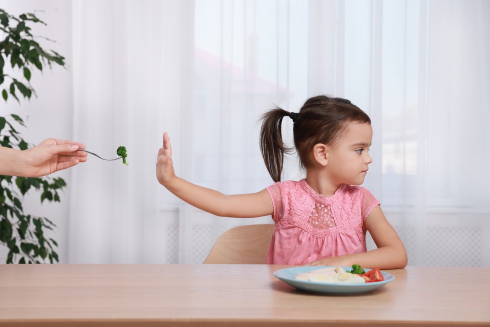 Cute little girl refusing to eat vegetables at home