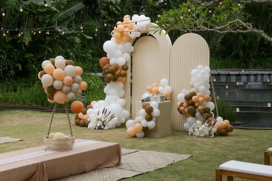 Creative gender neutral baby shower or birthday decoration in the garden. Bohemian style outdoor event set up with balloons. White cream peach caramel balloon arch kit.