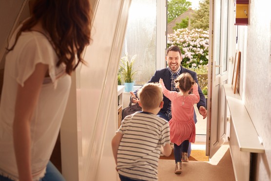 a young family rush to the front door as daddy comes home from work or a stint away