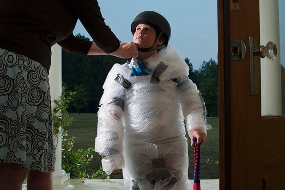 child wrapped in bubble wrap with mother doing up bike helmet