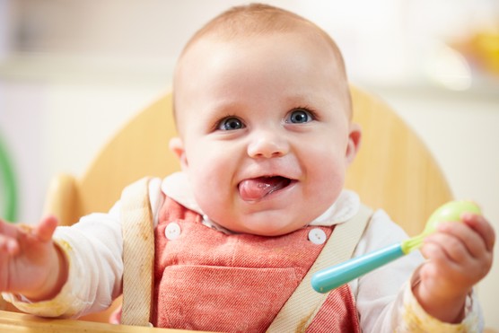 Portrait Of Happy Young Baby Boy In High Chair Waiting For Food