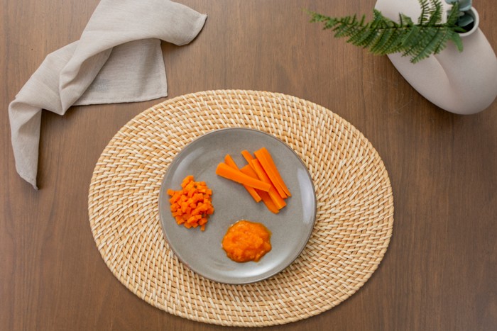 Different textures of cooked carrots for baby led weaning on a plate Presenting an array of carrot textures, from creamy puree to crunchy sticks, perfect for introducing solid foods in baby-led weaning
