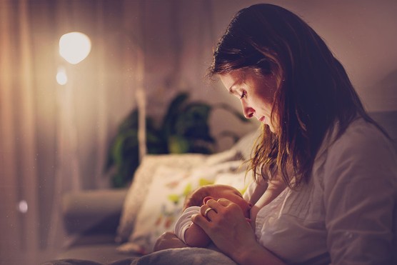 mother with brown hair breastfeeding her baby son in the night