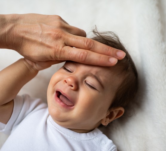 parent feeling forehead of baby with fever