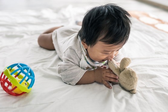 baby on tummy playing with toys
