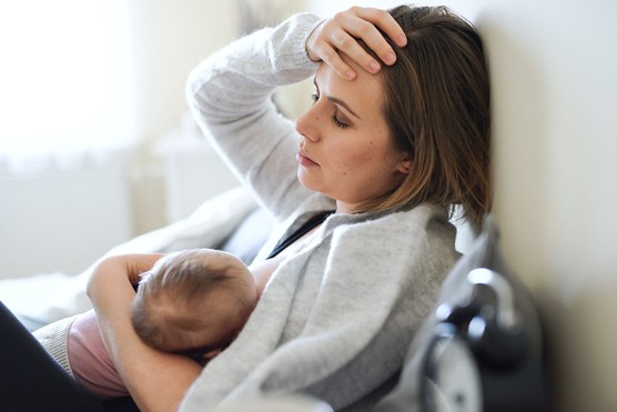 tired mother struggling with breastfeeding and looking stressed