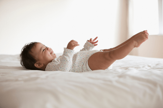 baby stretching out feet on bed